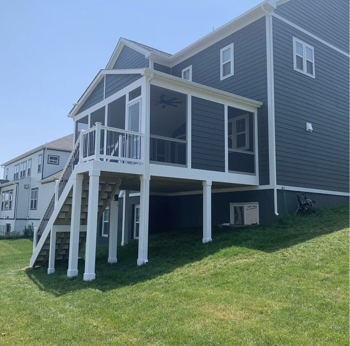 Elevated screened porch on white columns with stairs to the lawn